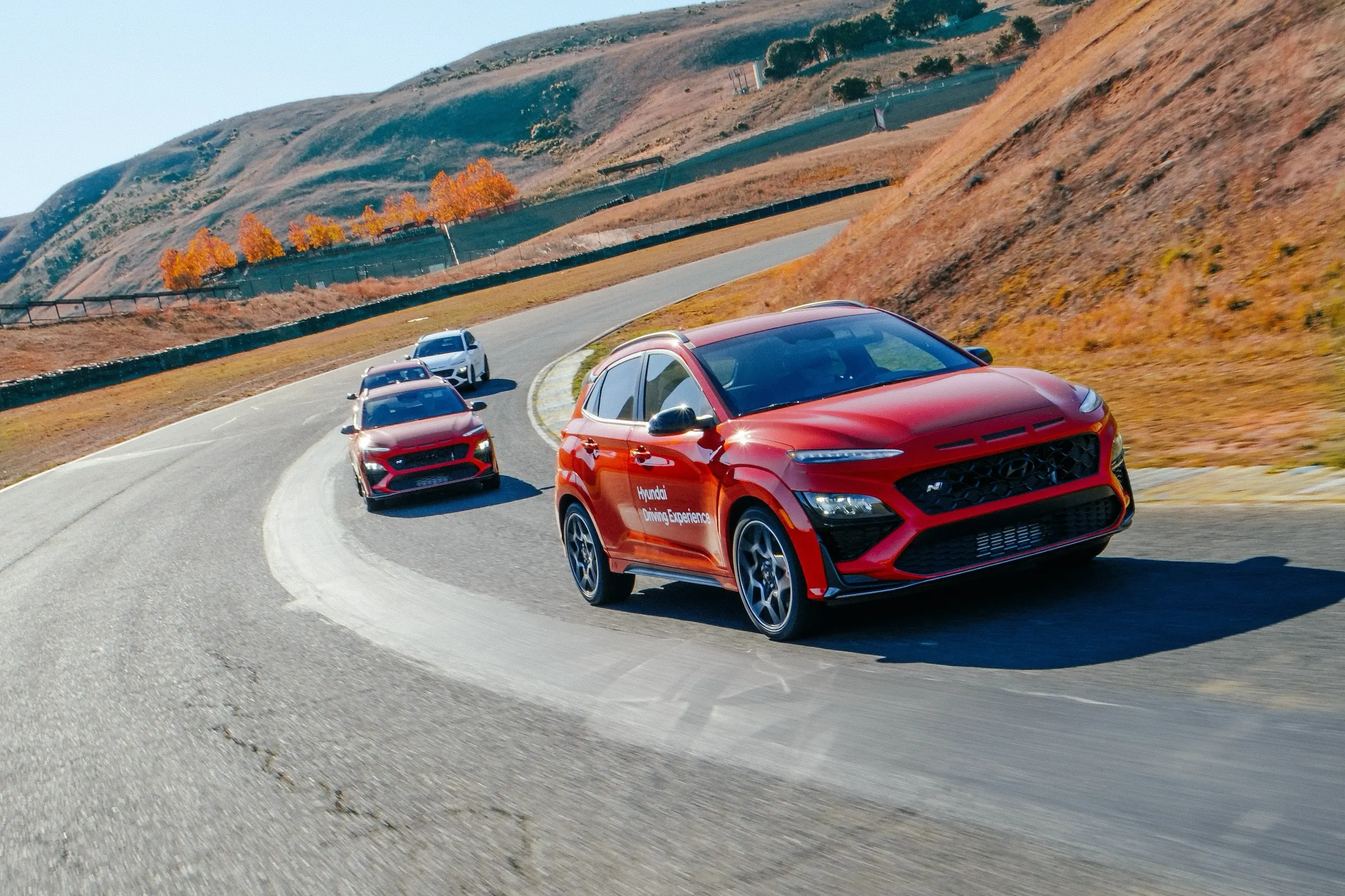Vier Hyundai Kona, die hintereinander durch eine große Kurve fahren. Im Hintergrund erkennt man die für Sonoma typischen Hügel.
