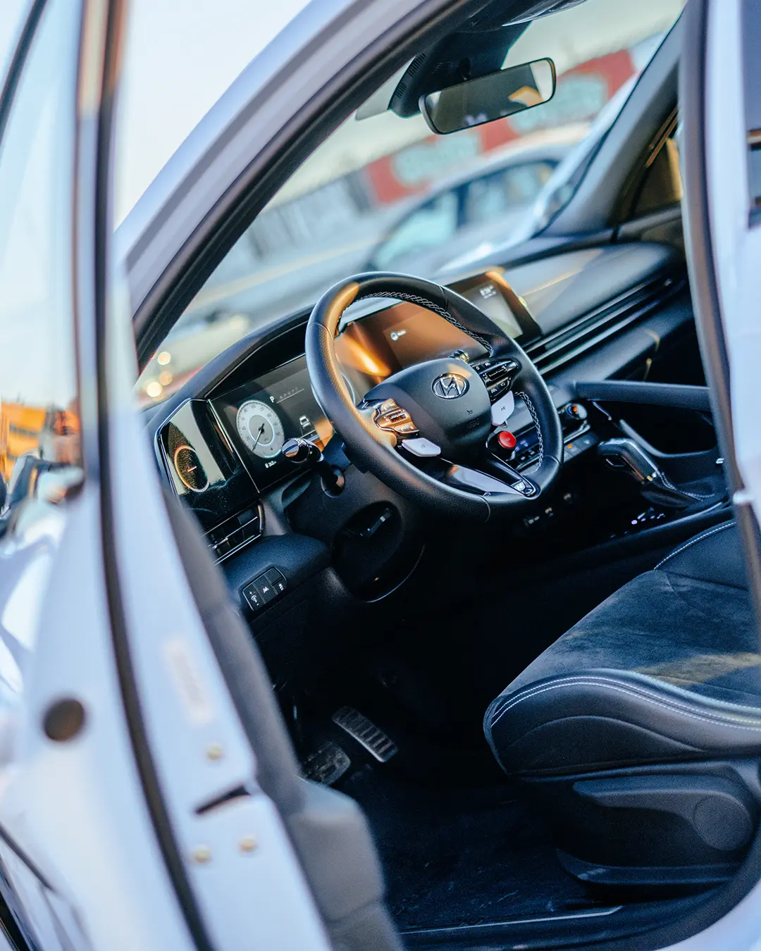 Der Blick durch die offene Fahrertür zeigt das Cockpit eines stehenden Fahrzeugs in der Boxengasse.